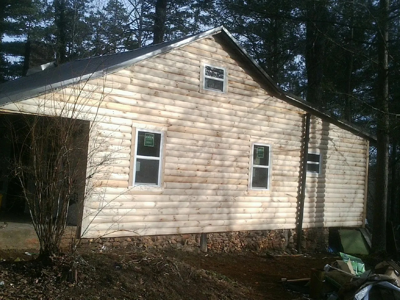 New log siding and dark metal roofing on a gable end in Norton